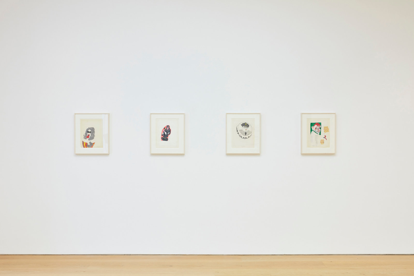 An installation view of four Karl Wirsum framed works on paper hanging on a wall horizontally.