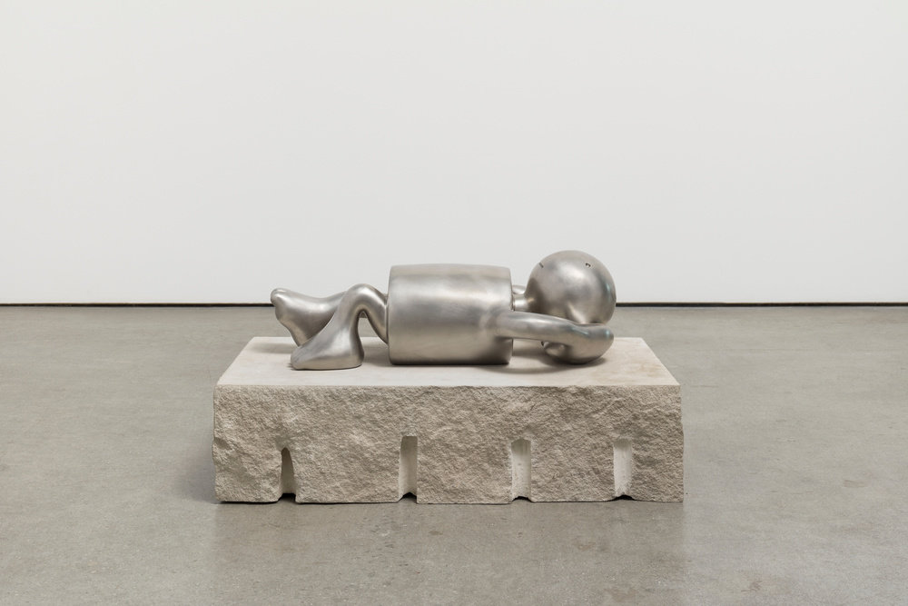 stainless steel figure lying down, arms behind his head 