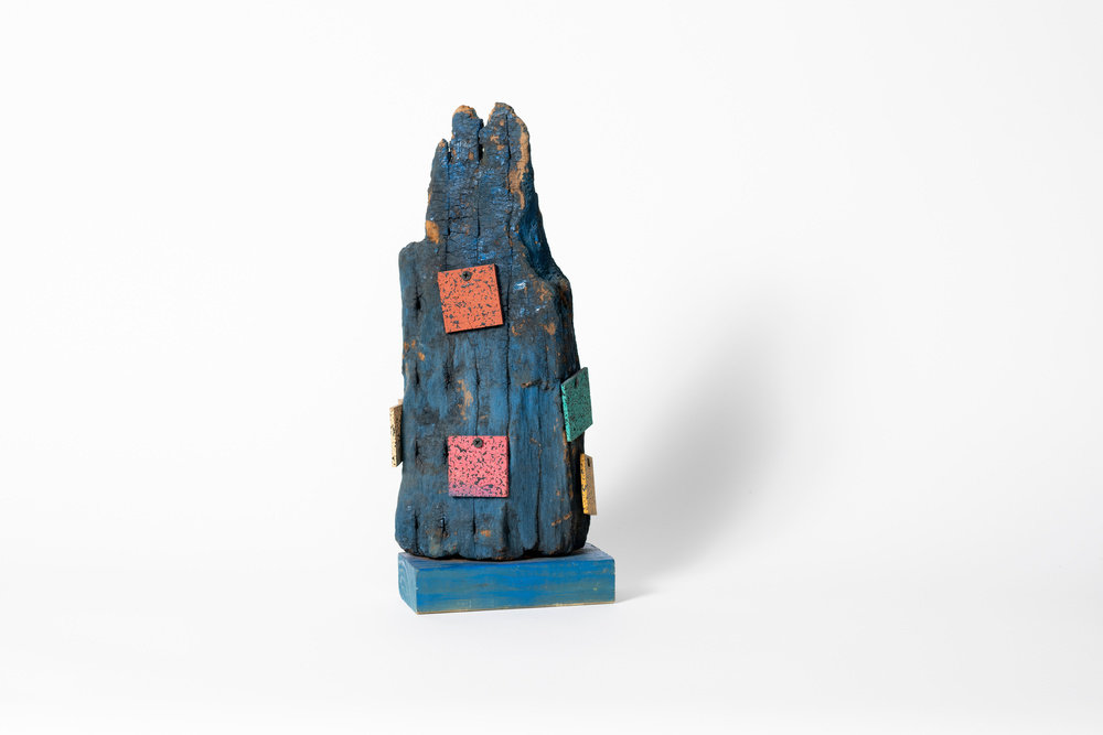 A sculpture by Lonnie Holley composed of found wood, flooring samples, nails, and paint. 