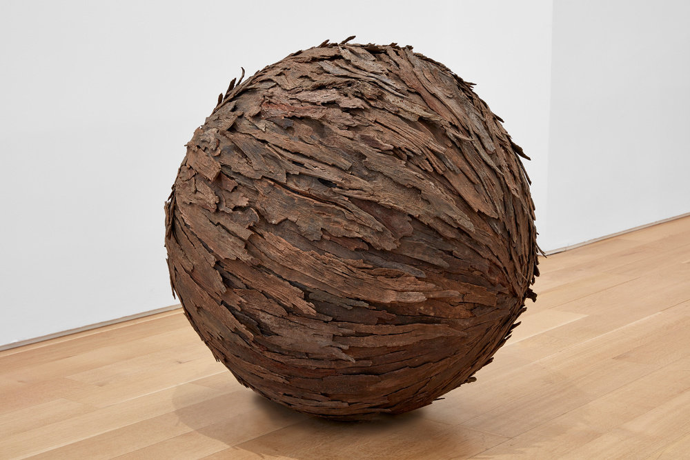 A spherical sculpture made of wood and bark that resembles a tree trunk by Lars Fisk. 