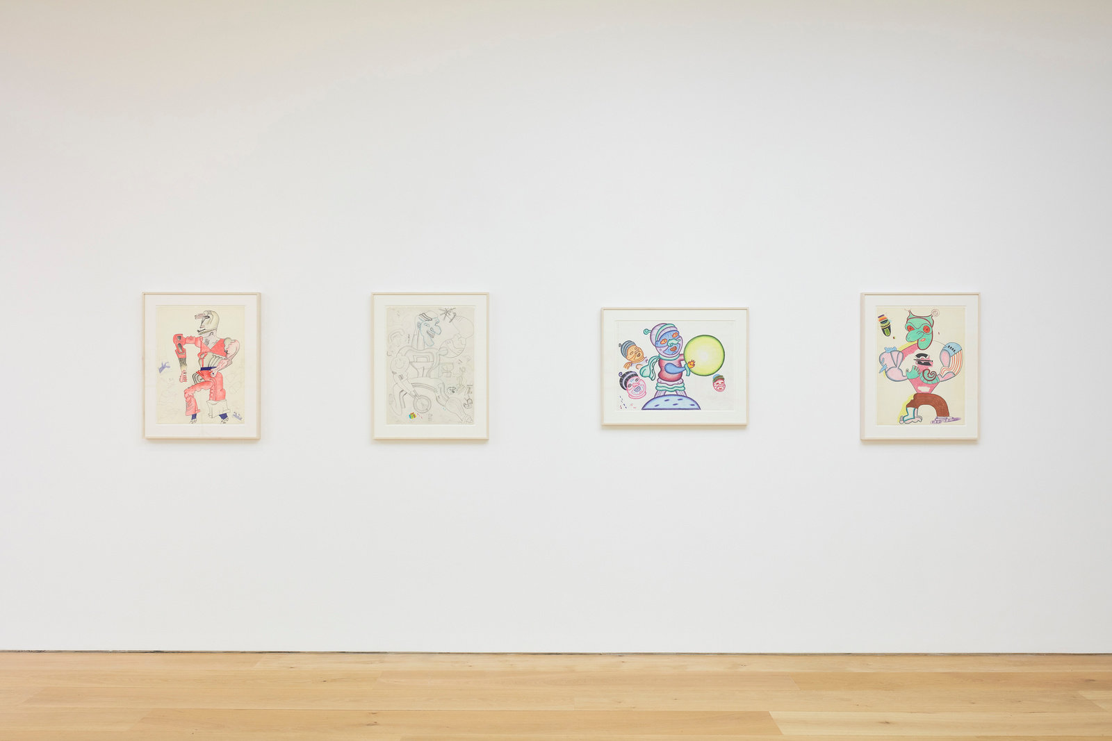 An installation view of four Karl Wirsum framed works on paper hanging on a wall horizontally.