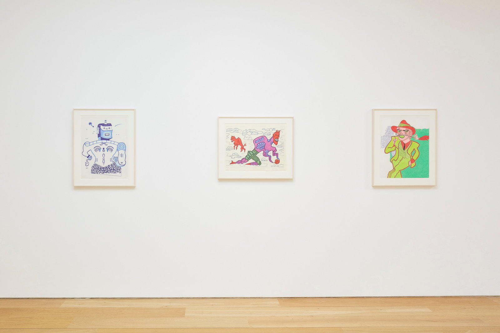 An installation view of three Karl Wirsum framed works on paper hanging on a wall horizontally.